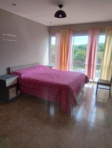 ein Schlafzimmer mit einem Bett mit einer lila Tagesdecke in der Unterkunft Casa de campo San Agustín in Cerrillos