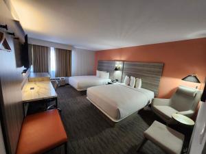 a large hotel room with two beds and a chair at The Grand Inn Peoria in Peoria