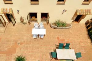 a patio with white tables and chairs on a brick floor at Can Lluna Rural House in Avinyonet de Puigventós