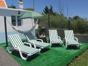 three chairs and a hammock on a green lawn at Casa Formiga in Fajã da Ovelha