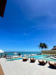 a swimming pool with a beach and a palm tree at Barra Bali Resort in Barra de São Miguel