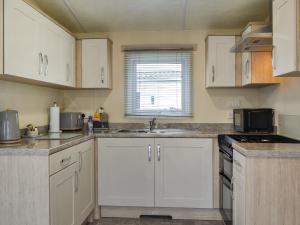 a kitchen with white cabinets and a sink at Rosie's Retreat - Uk46724 in Bridlington +5 photos