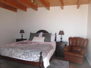 a bedroom with a bed and a chair at Casa Formiga in Fajã da Ovelha