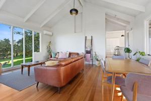 een woonkamer met een leren bank en een tafel bij Cape Cottages - Ollies View in Tanybryn