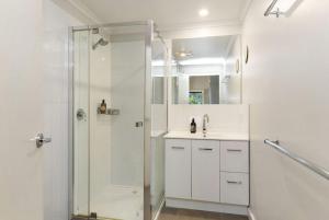 een witte badkamer met douche en wastafel bij Cape Cottages - Ollies View in Tanybryn +14 foto's
