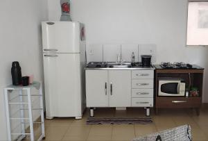 a kitchen with a white refrigerator and a microwave at Apartamento completo Valparaiso GO proximo de Brasilia DF BR040 in Valparaíso de Goiás