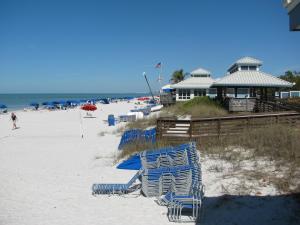 a group of beach chairs on the sand at the beach at Inn at Pelican Bay in Naples