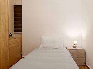 1 dormitorio con cama blanca y mesita de noche con lámpara en The Urban Nest, en Tal-Pietà