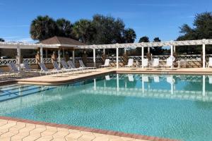a large swimming pool with chairs at Sunlit 2BR with Lanai on Golf Cart Path in Lady Lake