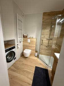a bathroom with a toilet and a shower and a washing machine at Nicole in Łagów