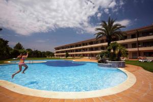 a woman jumping into a swimming pool at Apart-Hotel Golf Beach 35201 in Sa-Riera +7 photos