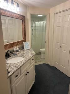 a bathroom with a sink and a toilet and a mirror at 3BR Lake Winnipesaukee Condo with Sandy Beach in Laconia +20 photos