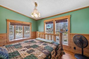 a bedroom with a bed and windows and a fan at Cozy 3BR with Firepit and Boat Slip Option in Moultonborough