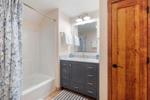 a bathroom with a sink and a tub and a mirror at 3BR with Hot Tub Arcade Games Near Lake and Slopes in Gilford +62 photos
