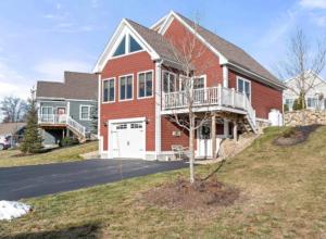a large red brick house with a balcony at 3BR plus Loft with Pool, Firepit, Walk to Boardwalk in Laconia