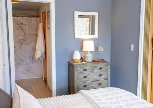 Un dormitorio con una cama y una cómoda con una lámpara. en The Cozy Cove - Walk to Concerts & Lake, en Gilford