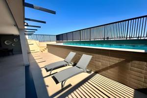 un grupo de sillas sentadas en un balcón junto a una piscina en Studio Encanto no Santa Maria., en Uberlândia