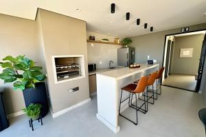 una cocina con encimera y algunas sillas naranjas en Studio Encanto no Santa Maria., en Uberlândia