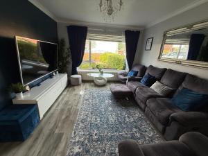 a living room with a couch and a flat screen tv at Room at quiet location close to Belfast in Carnmoney