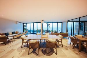 a dining room with a table and chairs and windows at Distrito Puerto, Ocean & Mangrove Views in Puerto Morelos