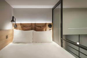 Un dormitorio con una cama grande con almohadas blancas. en Moxy London Piccadilly Circus, en Londres