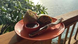 a plate of food with a sandwich and a dipping sauce at Monkey House Hostel in Tola