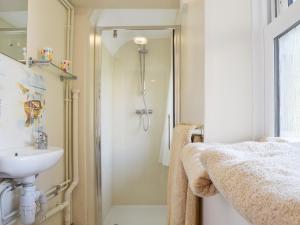 Un baño blanco con ducha y lavabo. en Steephill Lodge, en Saint Lawrence