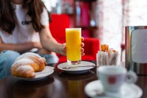 a person holding a glass of orange juice on a table at Domus Suite in Termoli