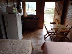 a kitchen with a refrigerator and a table and chairs at Recanto do Kevinho in Garopaba