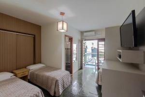 a hotel room with two beds and a flat screen tv at Pousada Cores do Mar | Conforto com Piscina em Bombinhas in Bombinhas +12 photos