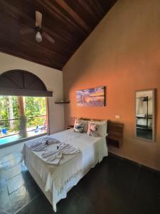 a bedroom with a large bed and a large window at Mambuca Village in Ubatuba