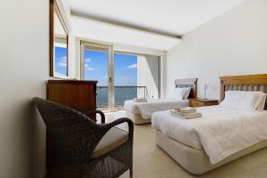 a bedroom with two beds and a chair and a window at Som do Mar Luxury Ocean Front Villa, Prime Location! in Luz +39 photos