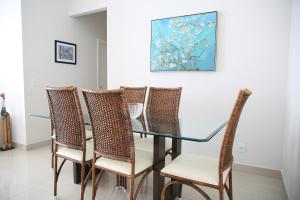 a glass table with wicker chairs and a painting at Apartamento Premium Vista da Serra in Diamantina