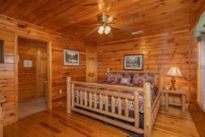 a log cabin bedroom with a bed and a ceiling fan at HIckernut Lodge by American Patriot Getaways in Walnut Grove