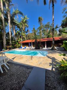 a swimming pool in front of a house with palm trees at Mambuca Village in Ubatuba