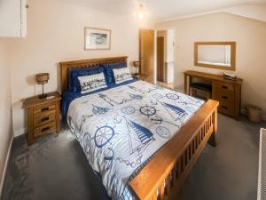 a bedroom with a bed with a blue and white bedspread at Little Netherleigh in Trearddur +6 photos