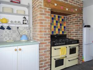 a kitchen with a stove and a brick wall at The Cottage in Wells