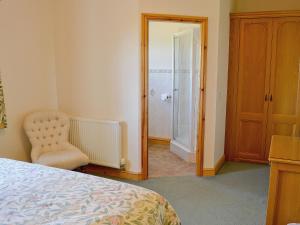 a bedroom with a bed and a chair and a mirror at Elidir Cottage in Llanwnda +6 photos