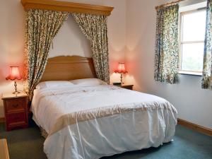 a bedroom with a bed and two windows at Elidir Cottage in Llanwnda
