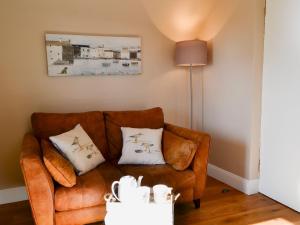 a living room with a brown couch with two pillows at Rock Cottage in Saint Abbs