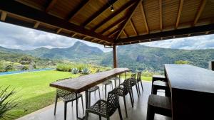 a table and chairs with a view of a mountain at Casa 02 Monte Boa Vista - Casa de 4 Suítes com Vista Deslumbrante in Teresópolis