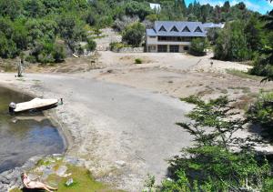 a house on a beach with a boat in the water at Aparts La Balconada by DOT Suites in Villa Pehuenia