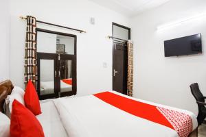 a bedroom with a bed with red pillows and a tv at Hotel O Devi Palace Inn in Gurgaon