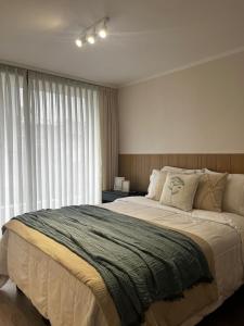 a bedroom with a large bed and a large window at NM Departamentos Amoblados in Concepción
