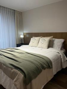 a bedroom with a large bed with white sheets and pillows at NM Departamentos Amoblados in Concepción