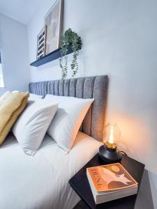 a bed with a side table with a book on it at Modern Central Flat with Garden & Parking in Southampton