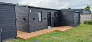 a black house with a wooden deck in a yard at Blokhus - tæt på by og strand in Blokhus