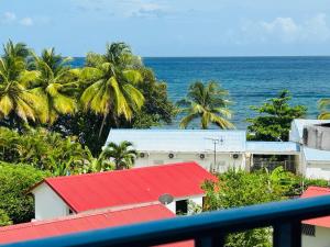 a view of the ocean from a balcony with a red roof at Studio Blue Wave Diamond, vue mer in Le Diamant