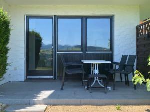 a patio with chairs and a table and windows at Neu - Ferienwohnung Allgäuparadies - Traumhafte Aussichten mitten in der Natur des Westallgäus in Oberreute +15 photos