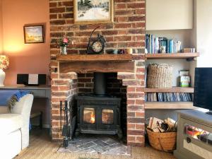 a brick fireplace with a stove in a living room at Beehive Cottage in Wittersham
